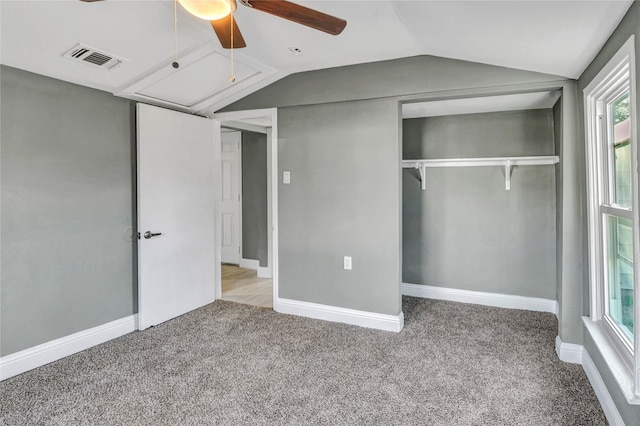 unfurnished bedroom featuring visible vents, carpet, attic access, vaulted ceiling, and a closet