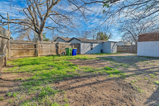 view of yard with an outbuilding, a fenced backyard, and a shed