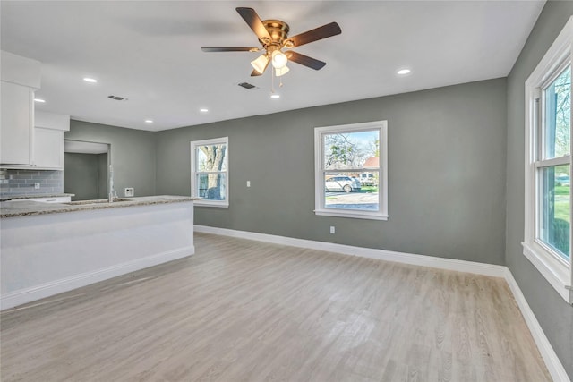 interior space with visible vents, baseboards, plenty of natural light, and white cabinets