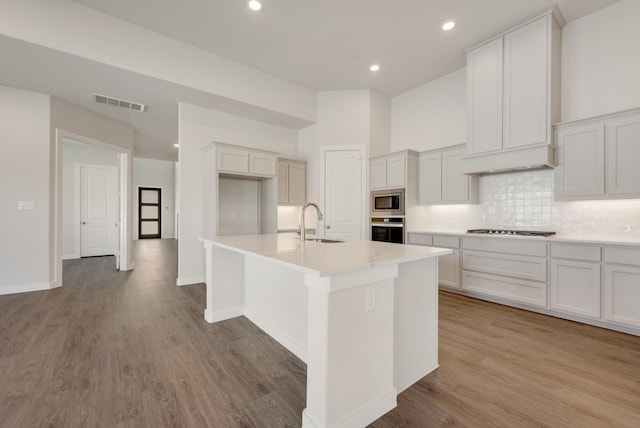 kitchen with visible vents, backsplash, appliances with stainless steel finishes, light wood-style floors, and a sink