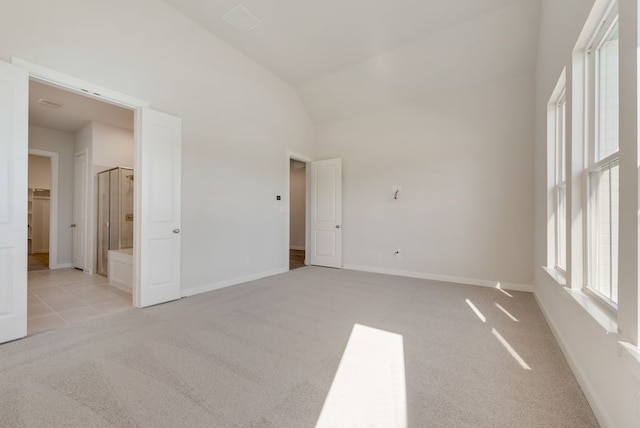 empty room with light tile patterned floors, baseboards, light carpet, and high vaulted ceiling