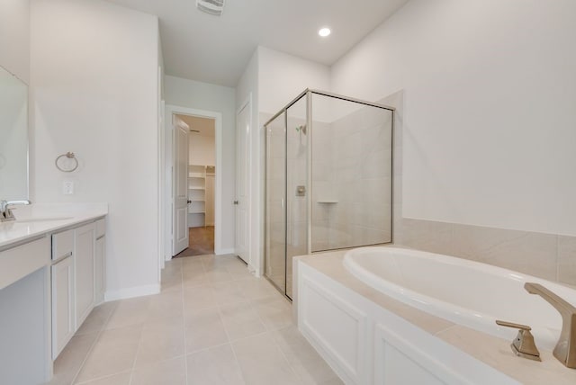 bathroom with a walk in closet, a shower stall, a bath, and tile patterned flooring