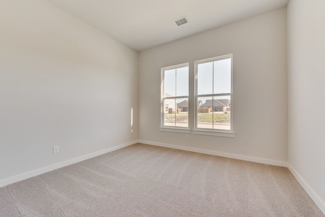 unfurnished room with baseboards, visible vents, and light carpet