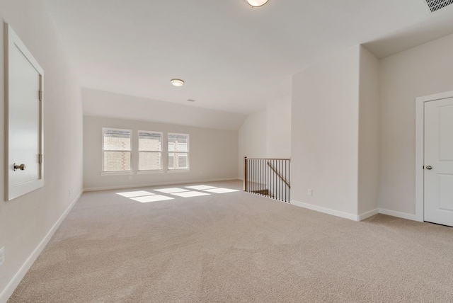 carpeted empty room featuring visible vents, baseboards, and vaulted ceiling