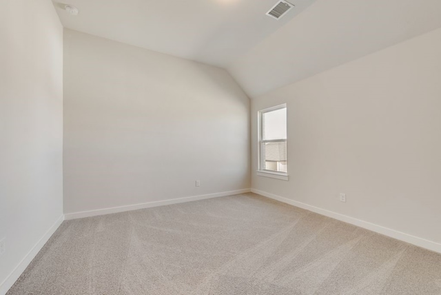 empty room with visible vents, baseboards, light colored carpet, and vaulted ceiling