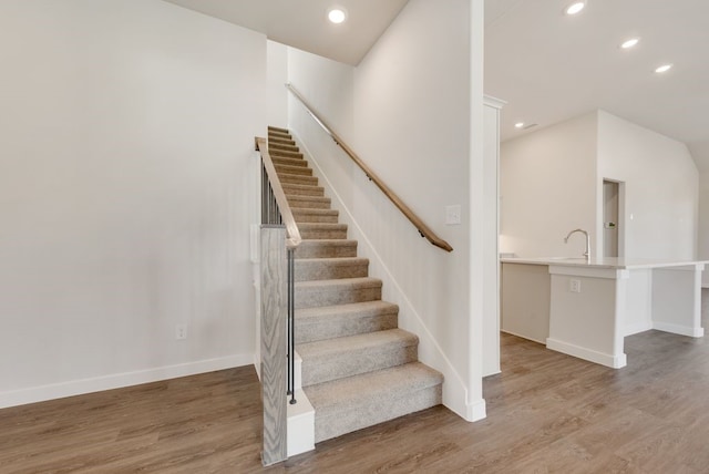 stairway with recessed lighting, wood finished floors, and baseboards