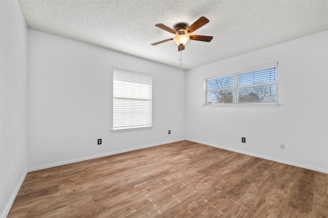 empty room featuring a ceiling fan, plenty of natural light, and wood finished floors