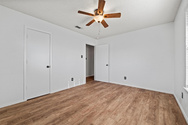 unfurnished bedroom with a textured ceiling, baseboards, visible vents, and light wood-type flooring