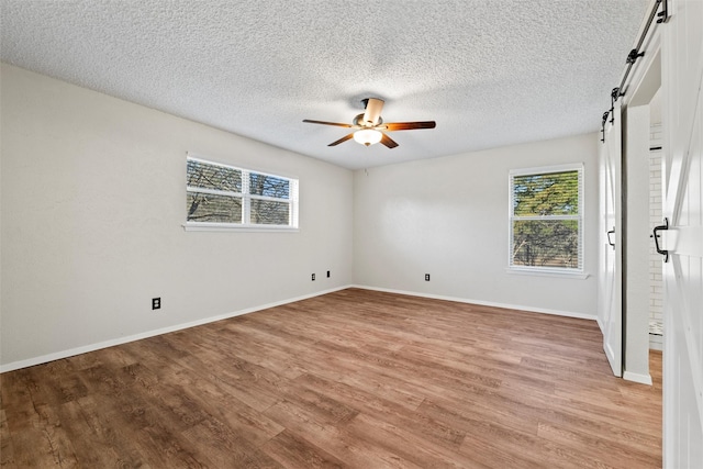 spare room with a wealth of natural light, light wood-style flooring, baseboards, and a ceiling fan