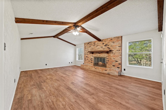 unfurnished living room with a wealth of natural light, a textured ceiling, ceiling fan, and wood finished floors