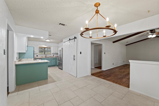 kitchen with ceiling fan with notable chandelier, open floor plan, freestanding refrigerator, a barn door, and light countertops