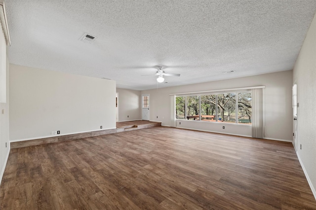 empty room with visible vents, a textured ceiling, wood finished floors, baseboards, and ceiling fan