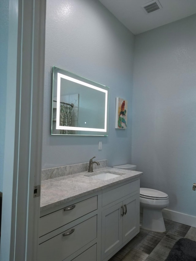 bathroom featuring visible vents, baseboards, toilet, and vanity