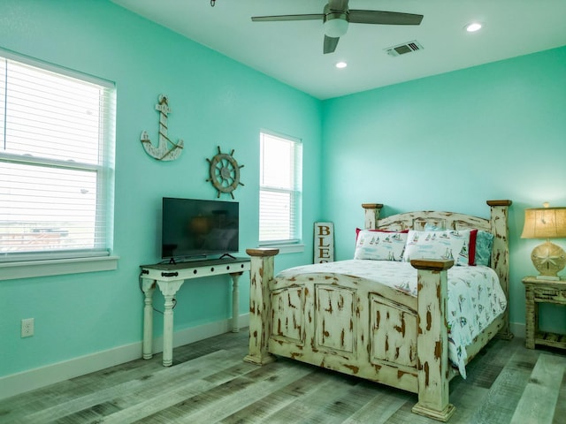 bedroom featuring multiple windows, wood finished floors, visible vents, and baseboards