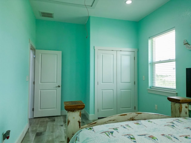 bedroom featuring visible vents, baseboards, a closet, and wood finished floors