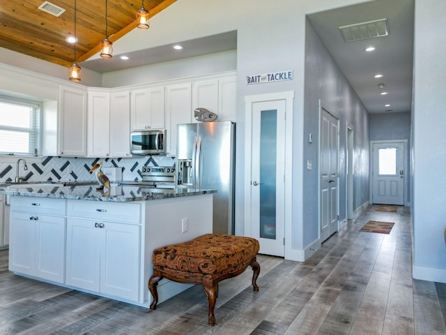 kitchen with stone countertops, stainless steel appliances, lofted ceiling, and visible vents