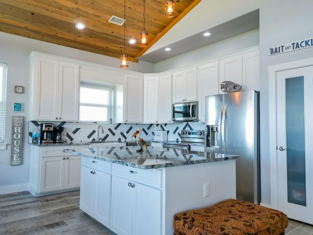 kitchen with visible vents, a center island, dark stone counters, decorative backsplash, and appliances with stainless steel finishes