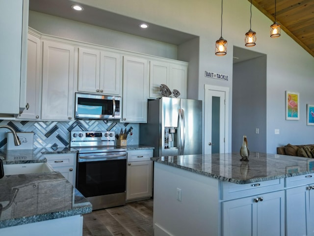 kitchen with dark stone counters, a sink, stainless steel appliances, white cabinets, and tasteful backsplash