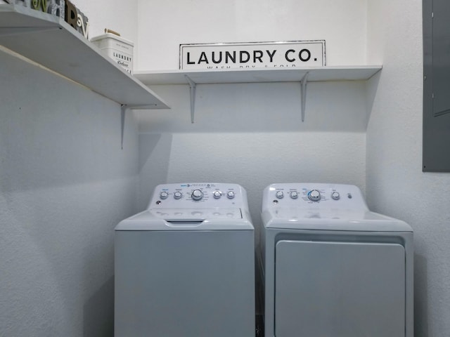 laundry area featuring electric panel, laundry area, a textured wall, and separate washer and dryer