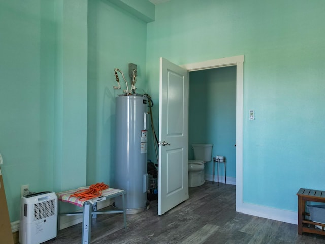 corridor with water heater, baseboards, and dark wood-style flooring