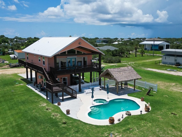 view of swimming pool featuring a pool with connected hot tub, stairway, a fenced backyard, a yard, and a patio area