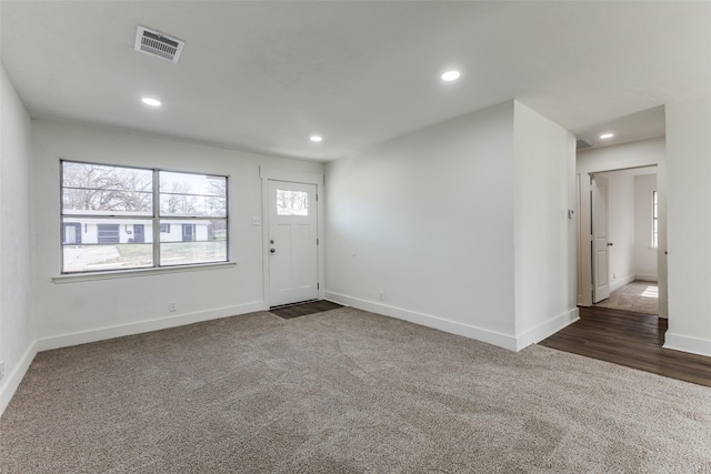 entrance foyer featuring recessed lighting, visible vents, baseboards, and dark carpet