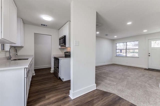 kitchen featuring visible vents, a sink, electric range oven, white cabinets, and stainless steel microwave