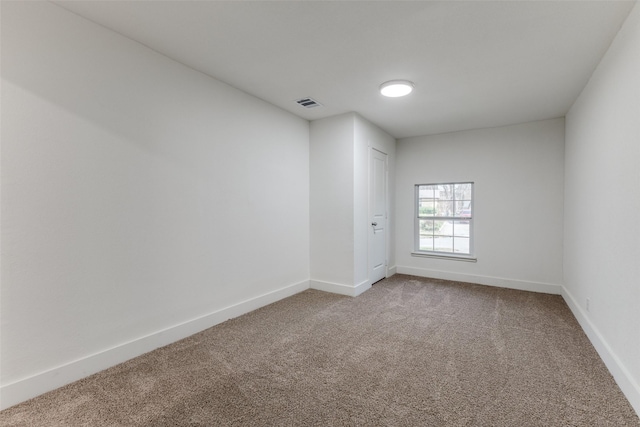 carpeted spare room featuring visible vents and baseboards