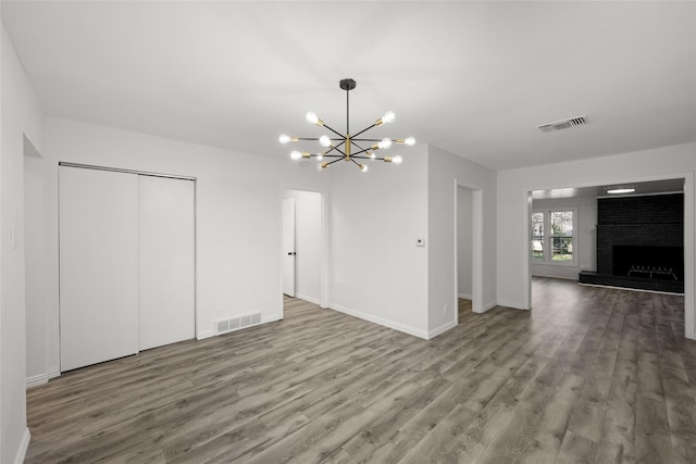 unfurnished living room featuring visible vents, wood finished floors, and a chandelier