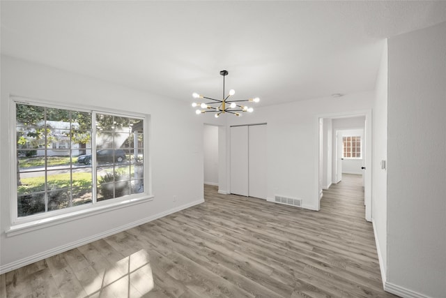 unfurnished dining area with visible vents, baseboards, a chandelier, and light wood finished floors