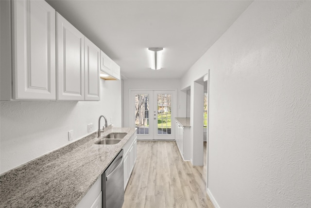 kitchen featuring light stone countertops, white cabinetry, a sink, french doors, and stainless steel dishwasher