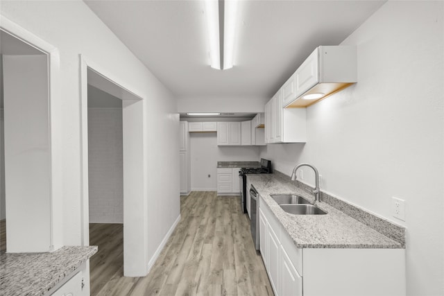 kitchen featuring a sink, light stone counters, appliances with stainless steel finishes, white cabinets, and light wood finished floors