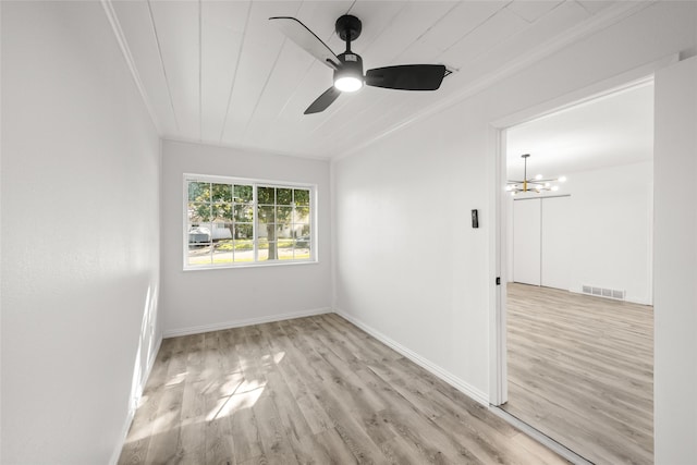 unfurnished room with ceiling fan with notable chandelier, wood finished floors, visible vents, and baseboards