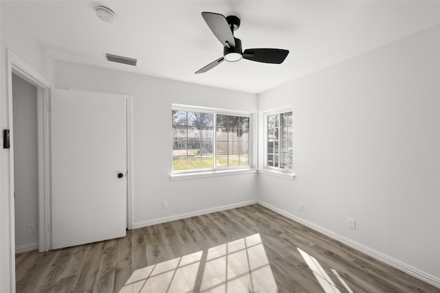 unfurnished room featuring visible vents, a ceiling fan, baseboards, and wood finished floors