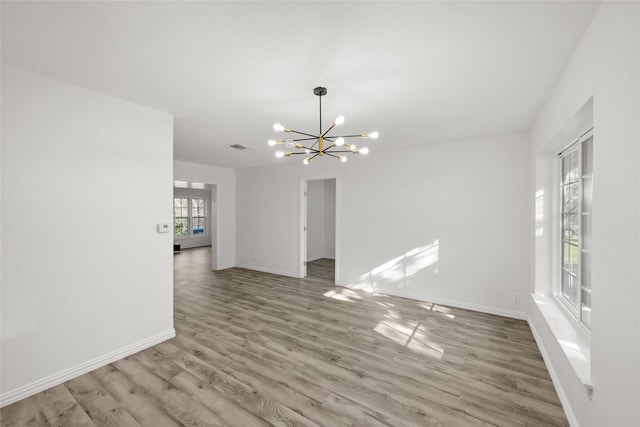 unfurnished room featuring visible vents, baseboards, an inviting chandelier, and wood finished floors