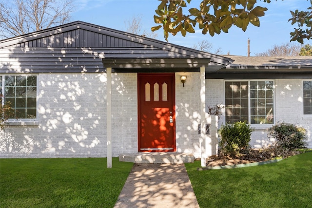 doorway to property with a yard and brick siding