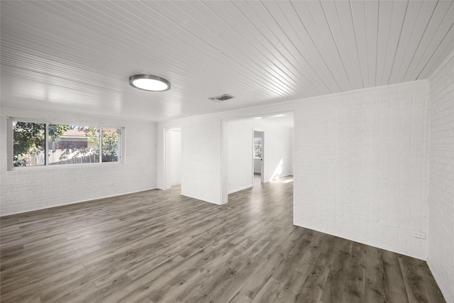 empty room featuring wooden ceiling, dark wood-style floors, visible vents, and brick wall