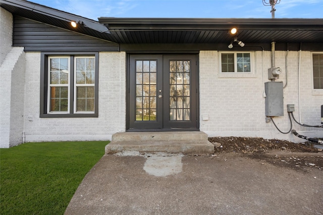 property entrance with french doors, a yard, and brick siding