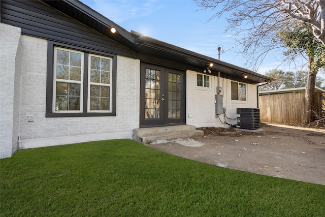 rear view of property with fence, a yard, central AC, french doors, and brick siding