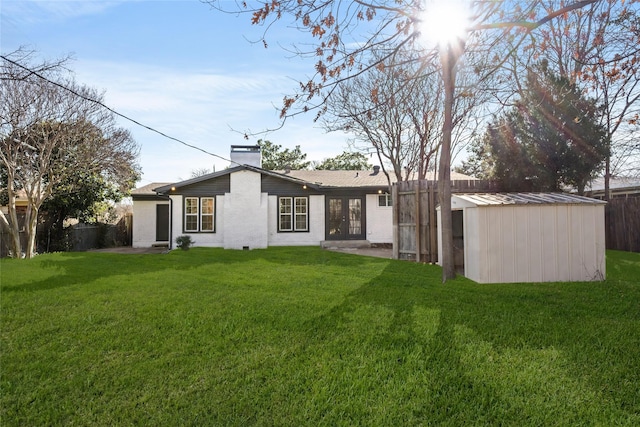 back of property with fence, a lawn, a chimney, an outdoor structure, and a storage unit