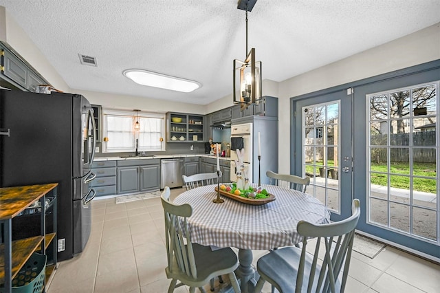 dining room with light tile patterned floors, visible vents, a textured ceiling, and french doors