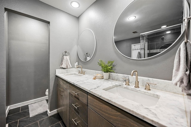 bathroom featuring double vanity, a stall shower, toilet, and a sink