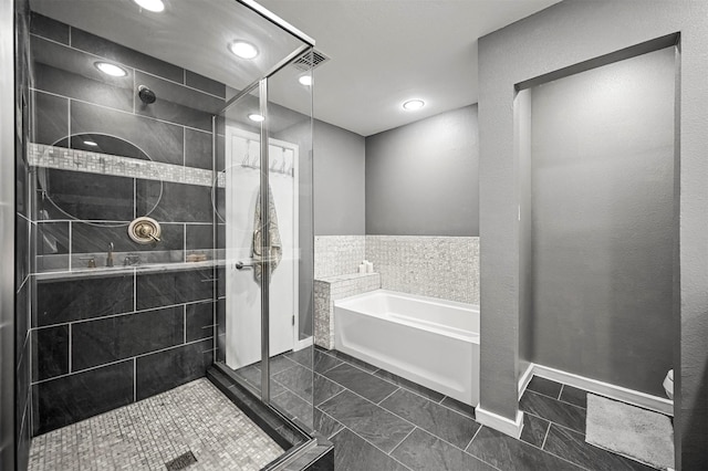 full bath with baseboards, a garden tub, tile patterned flooring, and a tile shower