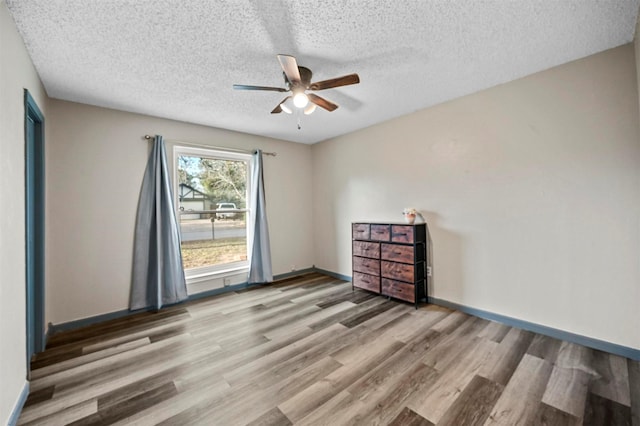 spare room featuring a textured ceiling, baseboards, ceiling fan, and wood finished floors