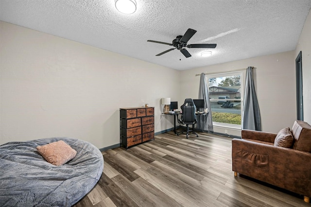 home office with a textured ceiling, a ceiling fan, baseboards, and wood finished floors