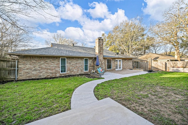 rear view of property with a patio, a fenced backyard, french doors, a yard, and brick siding