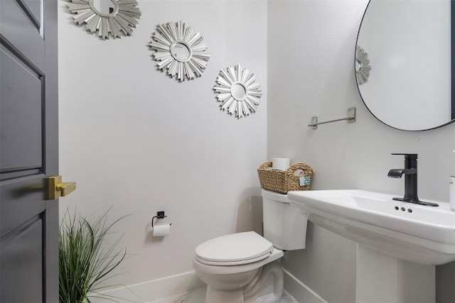 bathroom featuring a sink, baseboards, and toilet