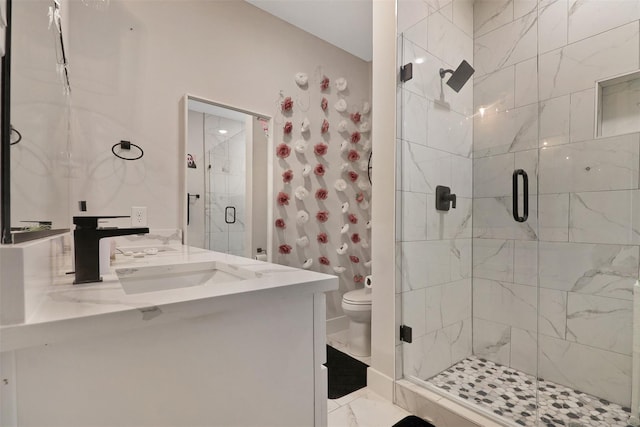 bathroom with a shower stall, vanity, toilet, and marble finish floor