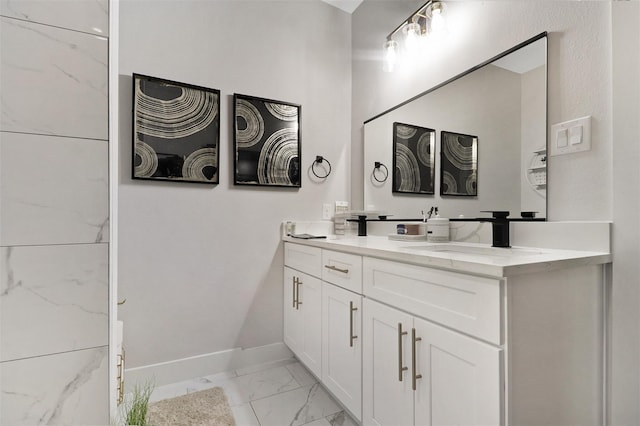 bathroom with double vanity, marble finish floor, baseboards, and a sink