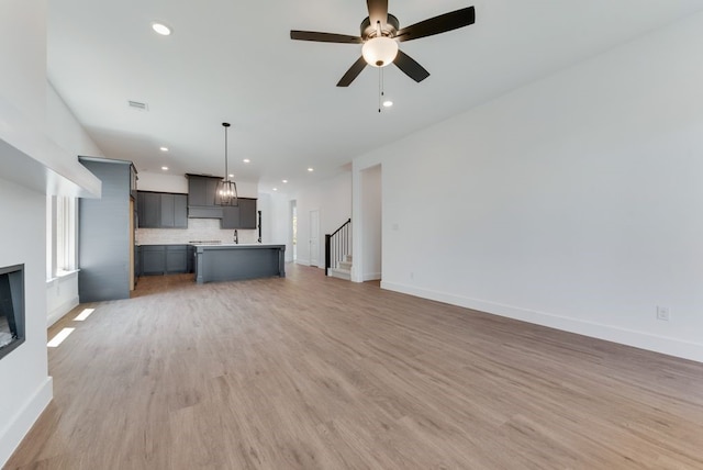 unfurnished living room featuring visible vents, baseboards, light wood-style flooring, and a ceiling fan